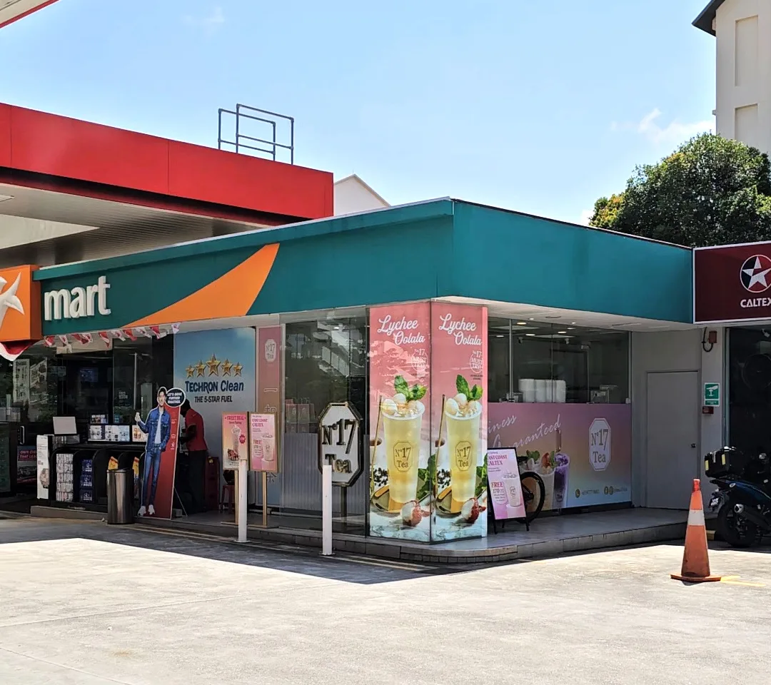 A No.17 Tea kiosk built into the corner of a petrol-station mart, with the gold octagon signboard and drink posters on the glass