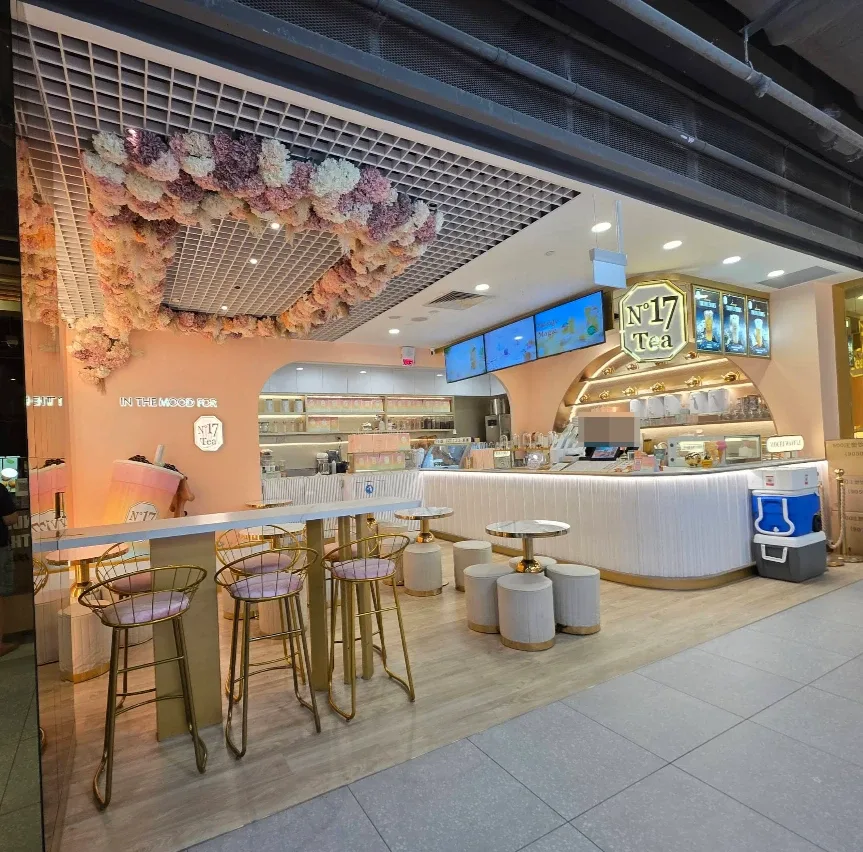 No.17 Tea flagship at The Woodleigh Mall — blush-pink columns, a dried-hydrangea ceiling, gold bar stools and the backlit octagon signboard over the counter